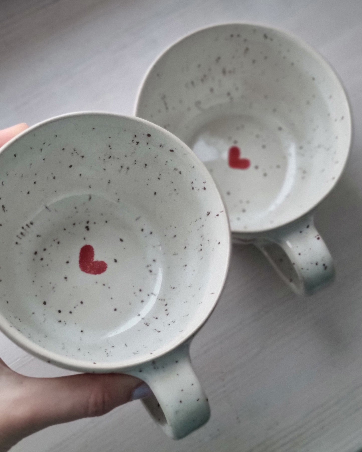 Two ceramic bowls with heart designs on a neutral background